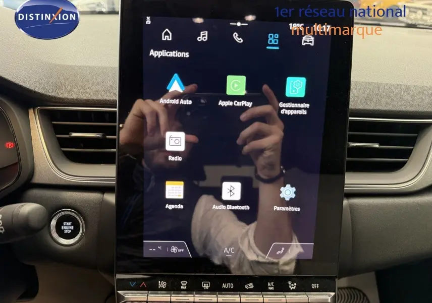 Vue intérieure centrée sur l'écran tactile du tableau de bord du Renault Captur gris Cassiopée, affichant les applications connectées.