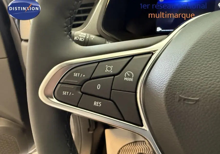 Gros plan sur les commandes au volant du Renault Captur gris Cassiopée, mettant en valeur les boutons de régulateur de vitesse.