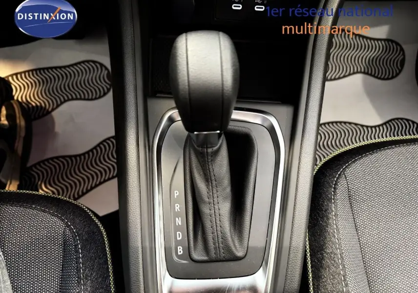 Le levier de vitesses automatique noir du Renault Captur 1.6 E-TECH Full Hybrid, vu de dessus, entouré de sièges gris.