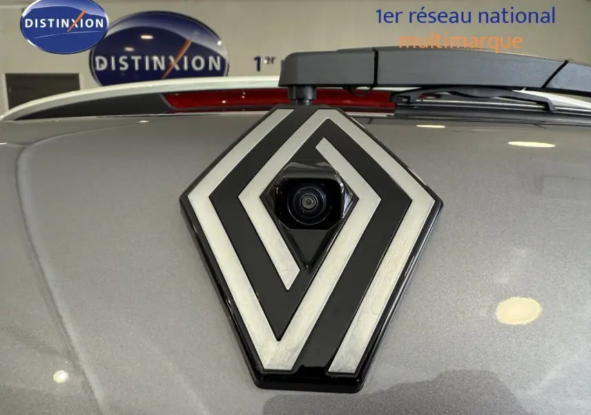 Gros plan sur le logo Renault gris métallisé avec caméra intégrée, sur le capot gris Cassiopée du Captur 2025.