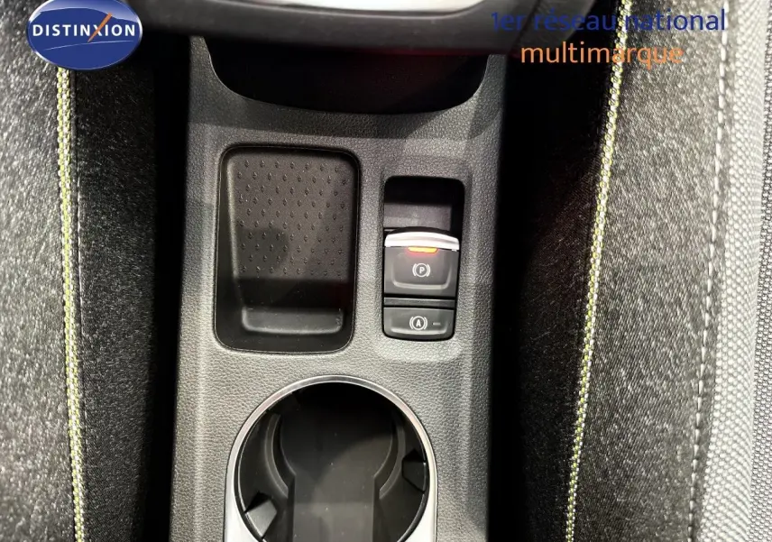 Gros plan sur la console centrale du Renault Captur gris cassiopée, avec bouton frein à main électrique et tissu gris à surpiqûres jaunes.
