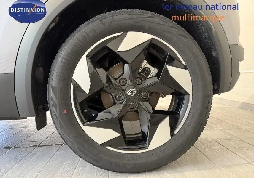 Gros plan sur la roue avant droite du Renault Captur gris Cassiopée Métal avec jante noire et argentée au design étoilé.