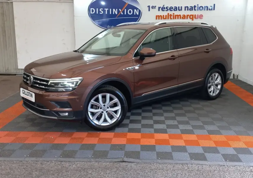 Volkswagen Tiguan Allspace marron vue de profil côté gauche en intérieur avec jantes alliage et toit chromé.