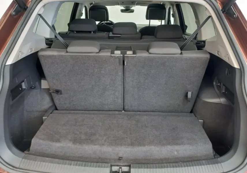 Vue arrière du coffre du Volkswagen Tiguan Allspace marron 2018 avec troisième rangée de sièges rabattus en tissu gris.