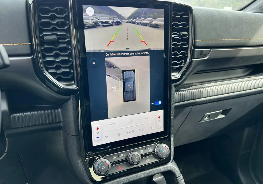 Vue intérieure du tableau de bord du Ford Ranger 2025, écran tactile central affichant la caméra 360° et commandes climatisation.