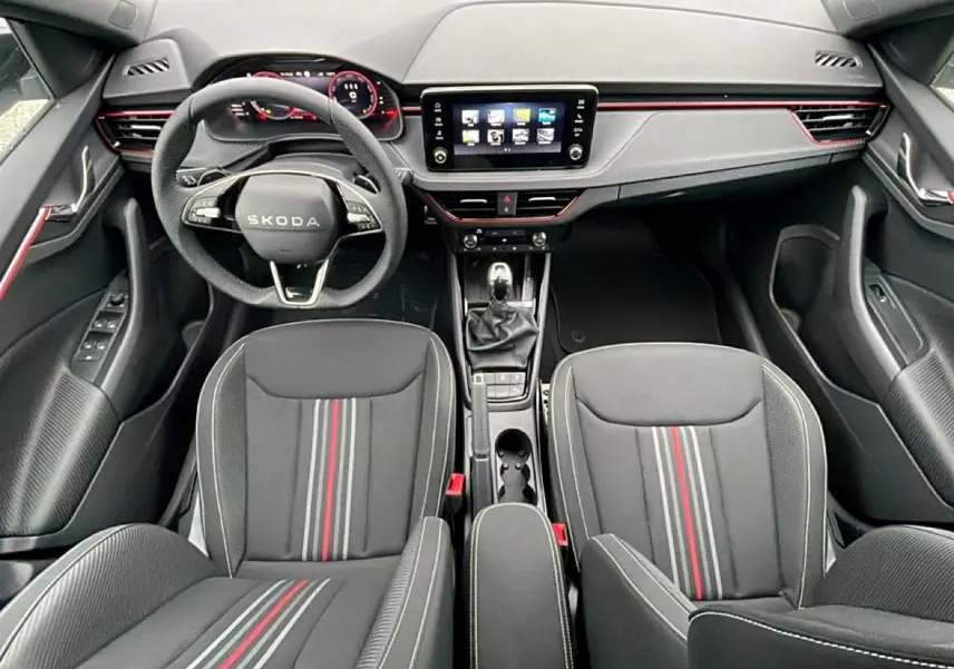 Vue intérieure frontale du Skoda Kamiq Monte Carlo 2026, sièges noirs avec bandes rouges et tableau de bord moderne.