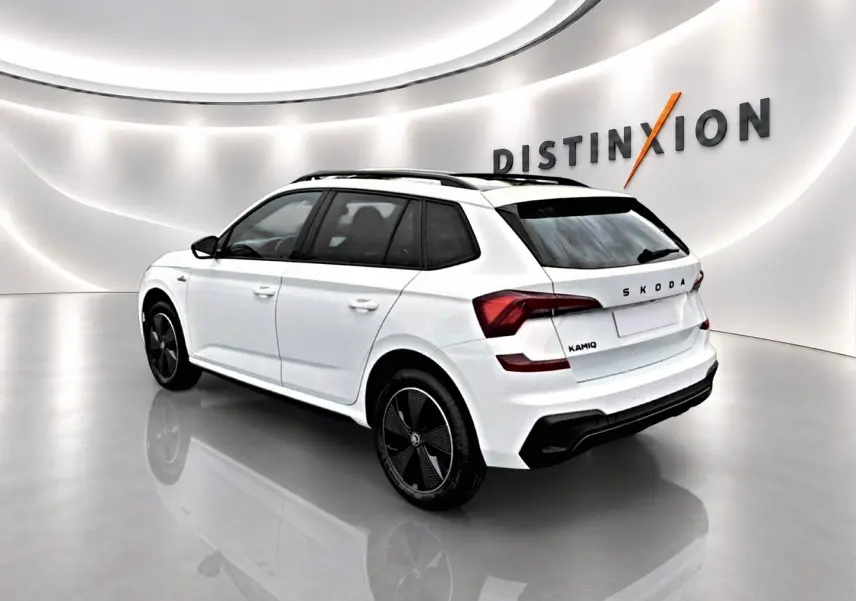 Vue 3/4 arrière droite d'un Skoda Kamiq blanc nacré avec jantes noires dans un showroom lumineux.