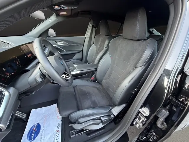 Vue intérieure côté conducteur du BMW X2 noir 2025, sièges sport en cuir et alcantara avec surpiqûres bleues.