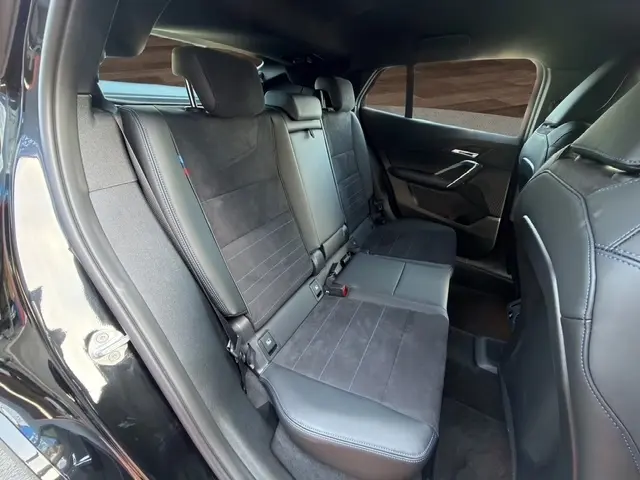 Vue intérieure côté droit sur la banquette arrière noire en cuir et alcantara du BMW X2 sDrive20d M Sport 2025.