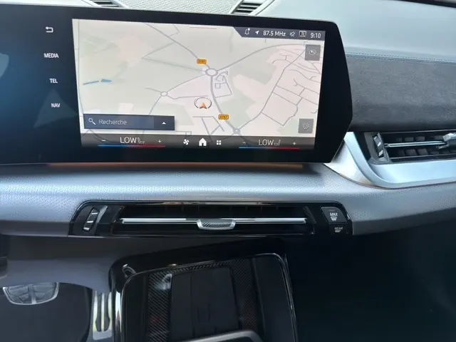 Vue rapprochée de l’écran tactile central du tableau de bord de la BMW X2 noire, affichant la navigation GPS.