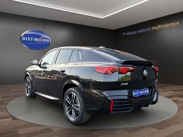 BMW X2 sDrive20d M Sport noir vue 3/4 arrière droit, avec jantes alliage et spoiler de toit visible.
