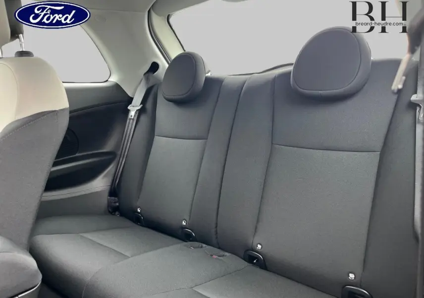 Vue intérieure sur la banquette arrière noire d'une Fiat 500 Ice White pastel, avec appuie-tête arrondis et ceinture de sécurité.