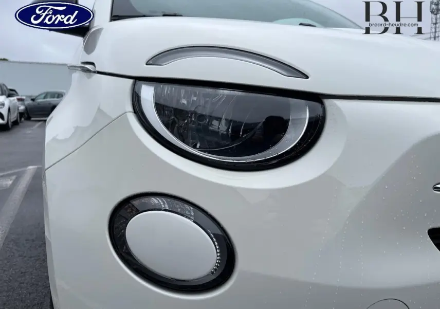 Gros plan sur l'avant gauche de la FIAT 500 Ice White pastel, mettant en valeur son phare rond et son antibrouillard.