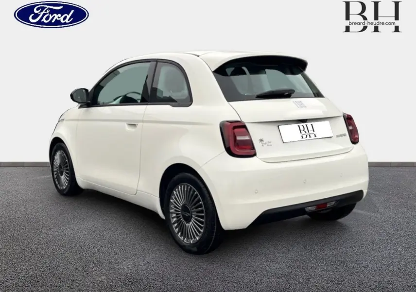 Vue 3/4 arrière droite de la FIAT 500 Ice White pastel avec jantes alu et becquet arrière visible sur fond neutre.