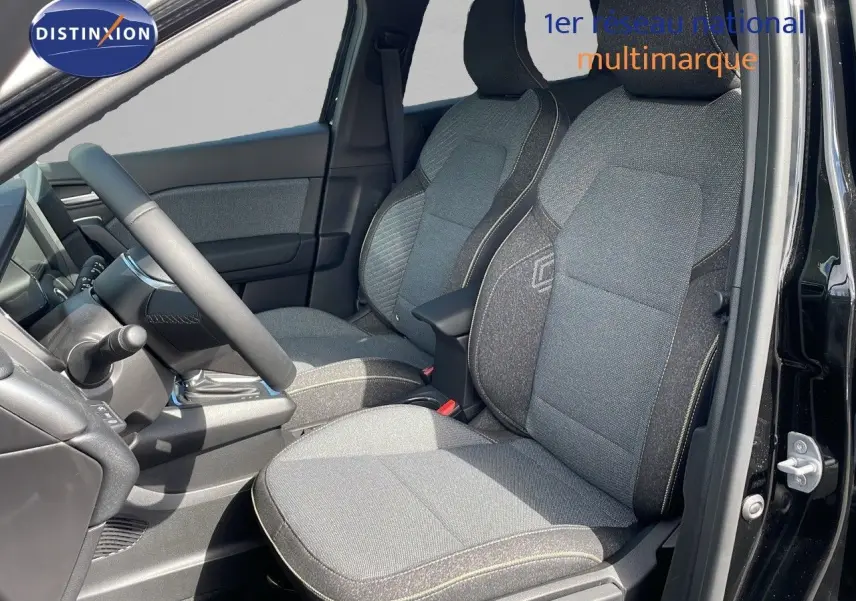 Vue intérieure côté conducteur du Renault Captur 2025, sièges tissu gris avec surpiqûres claires et tableau de bord noir.