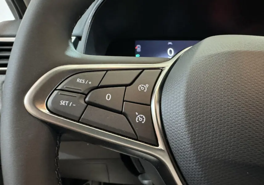 Gros plan sur les commandes du volant cuir synthétique de la Renault Clio gris clair Evolution Blue dCi 100, 2025.