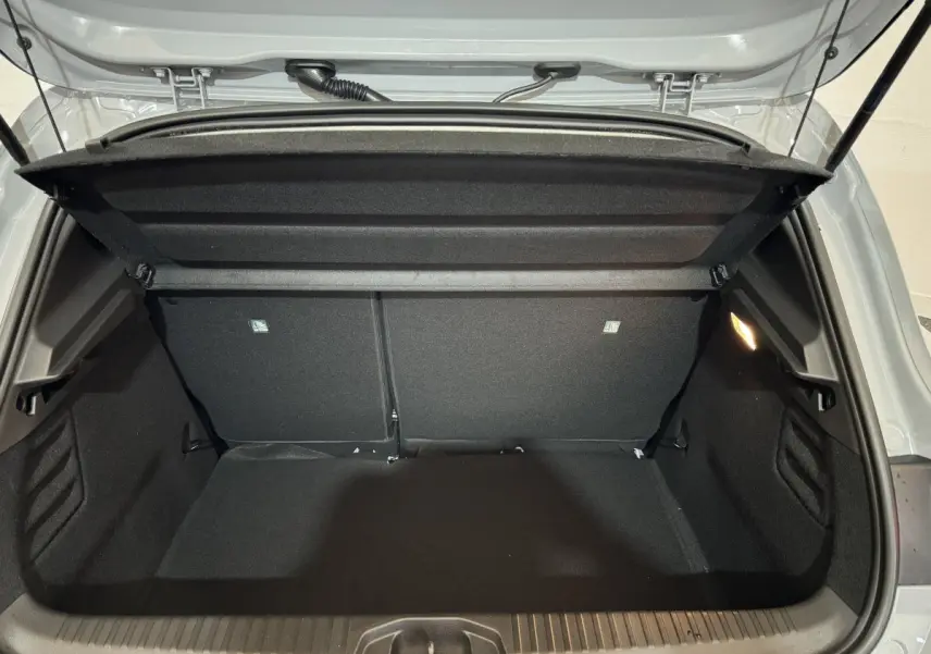 Coffre ouvert vu de l'arrière d'une Renault Clio gris clair 2025, intérieur spacieux et éclairage latéral.