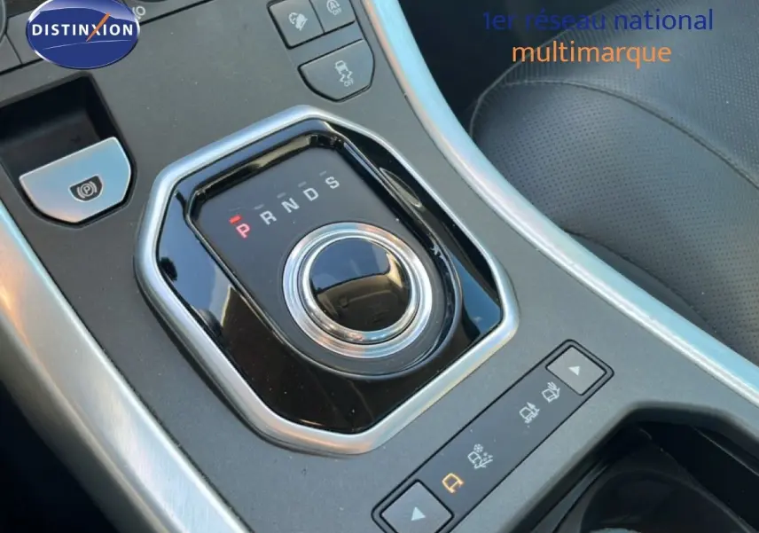 Gros plan sur la molette de sélection de la boîte automatique dans l'habitacle noir du Range Rover Evoque blanc.