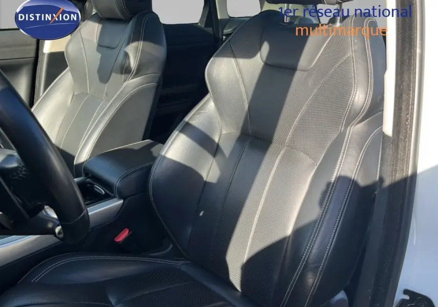 Gros plan sur les sièges avant en cuir noir du Range Rover Evoque blanc, avec détails de couture visibles.