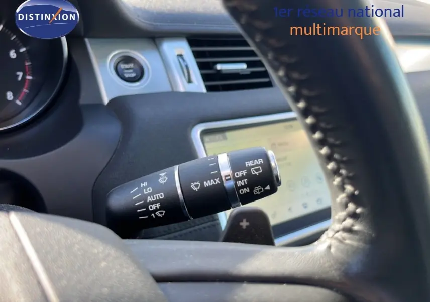 Gros plan sur la commande des essuie-glaces à l'intérieur d'un Range Rover Evoque blanc, avec volant en cuir noir visible.