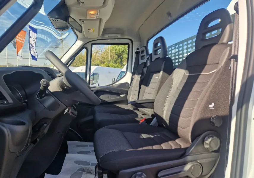 Vue intérieure côté conducteur de la cabine blanche Iveco Daily Chassis Cabine 2026, montrant les sièges noirs et le volant.