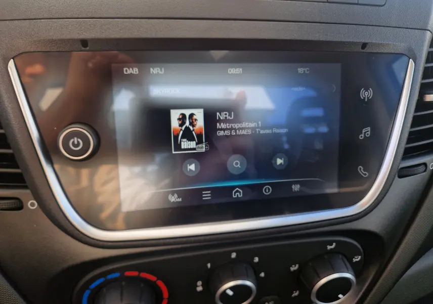 Écran tactile central du tableau de bord de l'Iveco Daily 2026 affichant la radio NRJ et les commandes de climatisation.