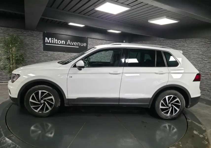 Volkswagen Tiguan blanc vu de profil côté gauche, avec jantes alliage 17 pouces et barres de toit.