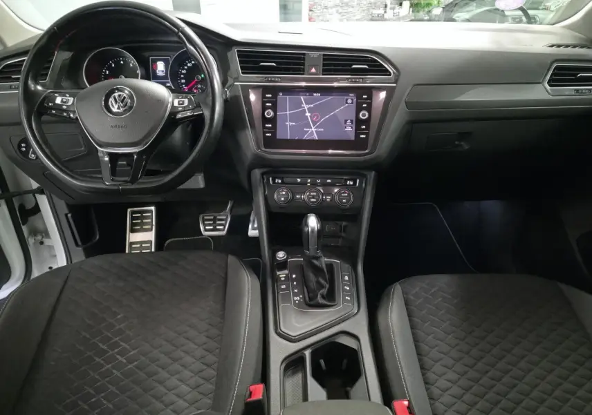 Vue intérieure avant du Volkswagen Tiguan 2019 blanc, tableau de bord avec écran tactile et volant multifonction cuir.