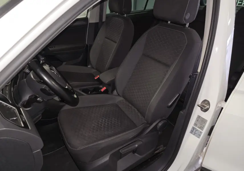 Vue intérieure côté conducteur du Volkswagen Tiguan blanc, sièges tissu noir à motif losanges.