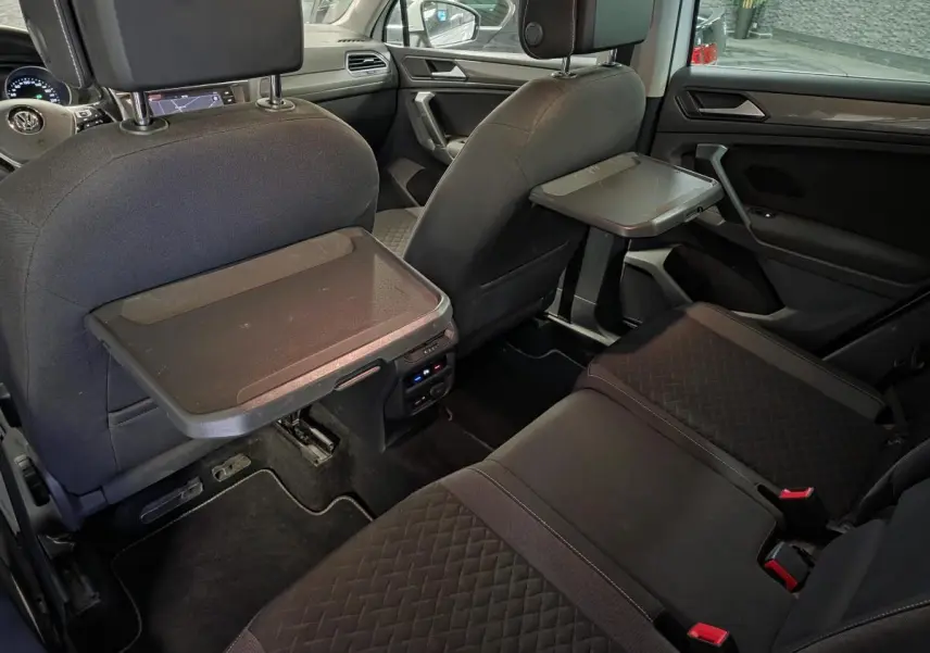 Vue intérieure arrière du Volkswagen Tiguan 2019 avec tablettes rabattables sur les dossiers des sièges avant et sellerie tissu noire.