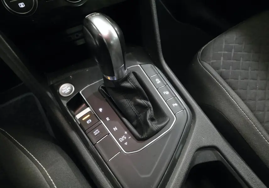 Gros plan sur le levier de vitesses automatique noir et argenté du Volkswagen Tiguan 2019, avec siège tissu gris à motifs.