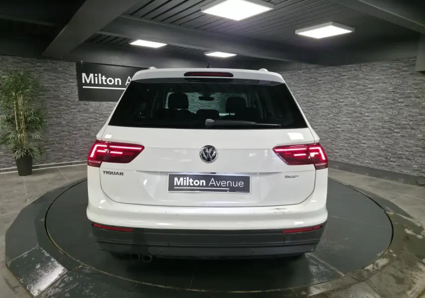 Vue arrière d'un Volkswagen Tiguan blanc avec feux LED allumés dans un showroom intérieur.