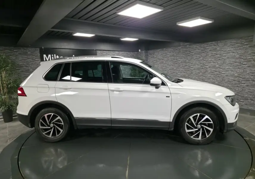Volkswagen Tiguan blanc vue de profil côté gauche, avec jantes alliage noires et toit ouvrant visible.