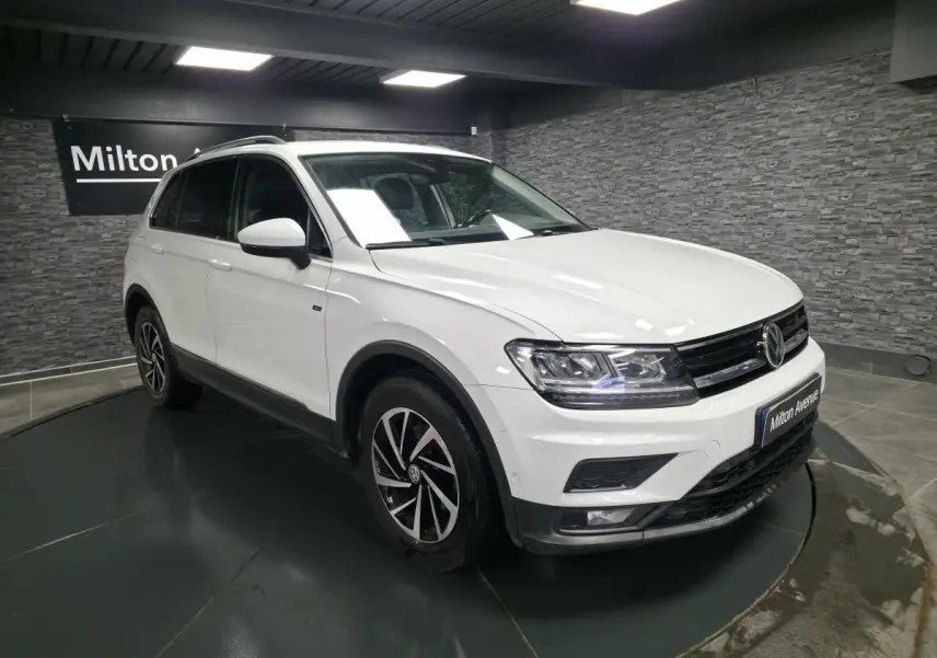 Volkswagen Tiguan blanc en 3/4 avant droit, avec jantes alliage et projecteurs LED allumés.
