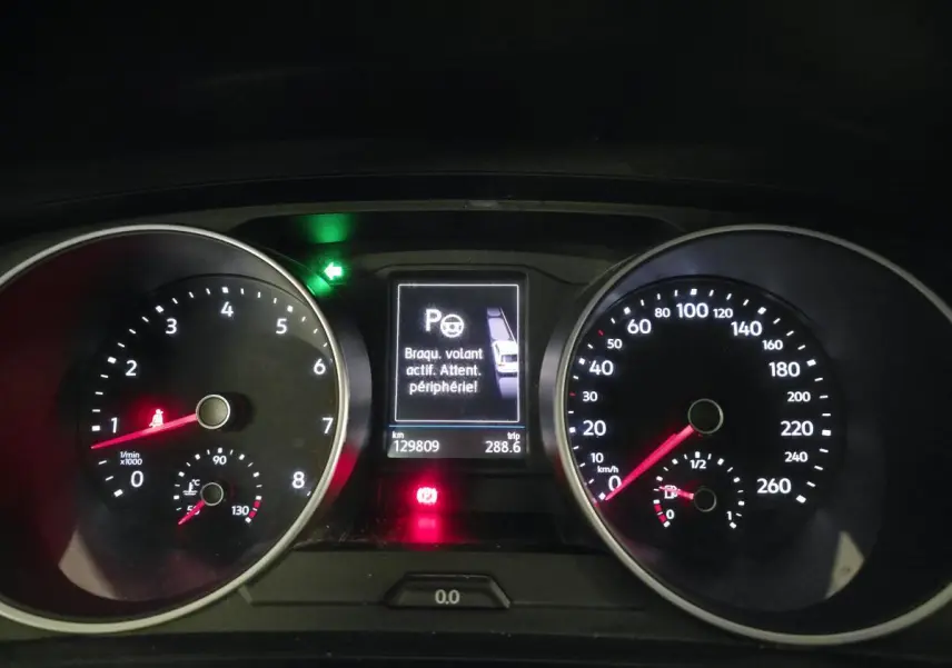 Vue rapprochée du tableau de bord du Volkswagen Tiguan blanc, affichant compte-tours, vitesse et alertes numériques.