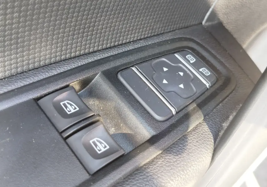 Gros plan sur les commandes électriques des vitres et des rétroviseurs côté conducteur du Renault Kangoo blanc Minéral 2023.