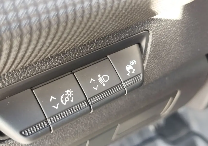 Gros plan sur les boutons de réglage de l'éclairage et de l'ESP dans un Renault Kangoo blanc minéral 2023.