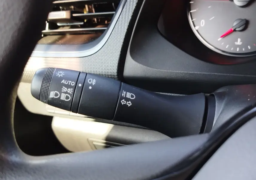 Gros plan sur la commande des feux à gauche du volant dans l'habitacle gris du Renault Kangoo blanc 2023.