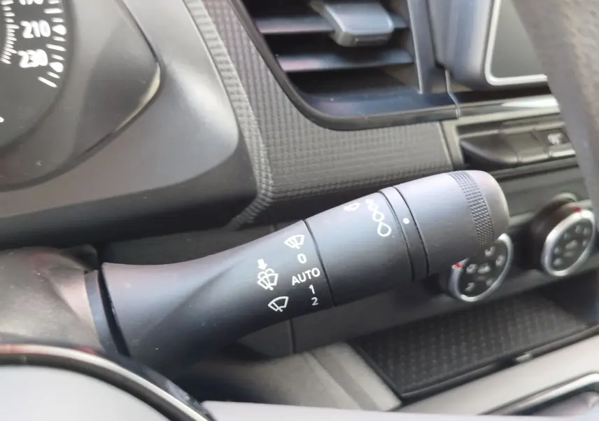 Gros plan sur la manette d’essuie-glace noire du tableau de bord intérieur du Renault Kangoo blanc 2023.