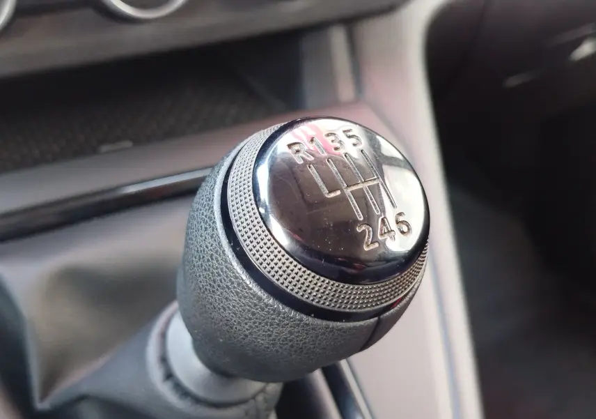 Gros plan sur le pommeau de la boîte manuelle du Renault Kangoo 2023, détail du levier de vitesses en cuir gris.
