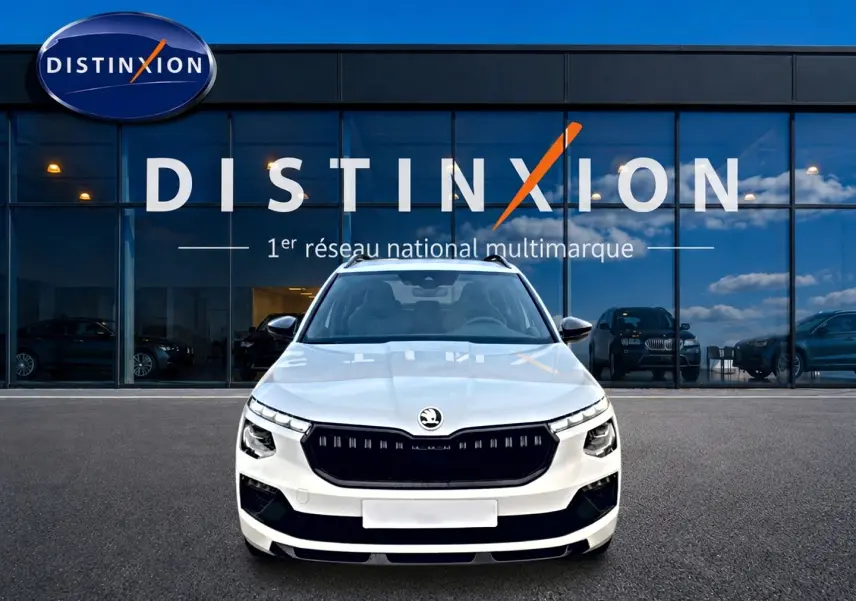 Vue frontale d'un Skoda Kamiq blanc nacré avec calandre noire et toit panoramique, devant une vitrine Distinxion.