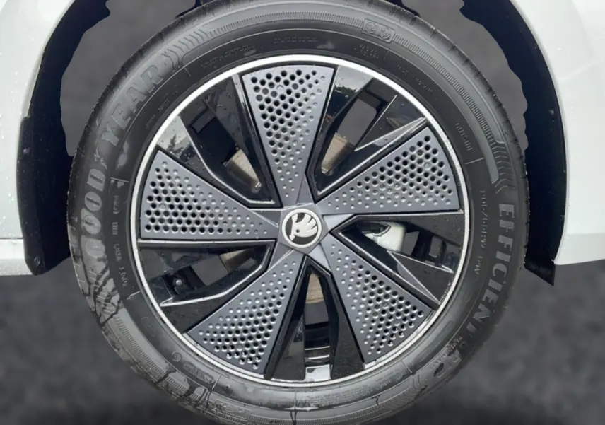 Gros plan sur la jante noire et argentée du côté gauche d’un Skoda Kamiq blanc nacré, avec logo central visible.