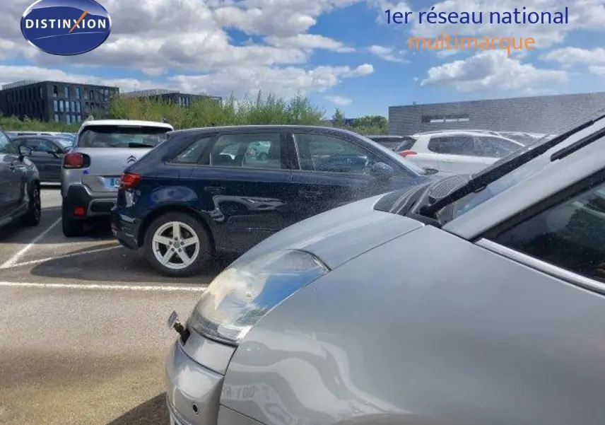 Vue rapprochée du côté avant droit d'une Citroën C4 Picasso gris alu métal sous un ciel partiellement nuageux.