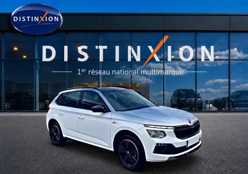 Vue 3/4 avant droite d'un Skoda Kamiq blanc nacré avec toit noir et jantes noires devant un showroom Distinxion.