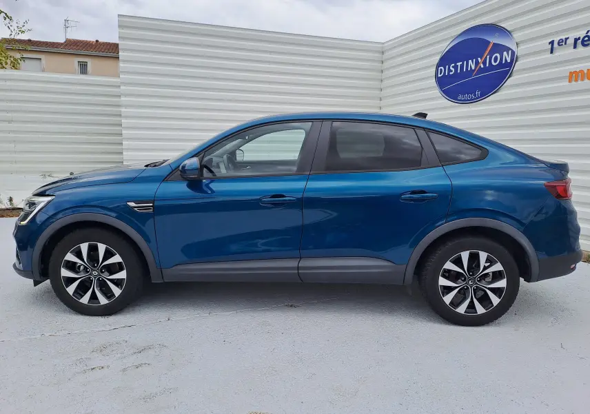 Profil côté gauche d'un Renault Arkana bleu Zanzibar metal 2023, SUV hybride avec jantes bi-ton et lignes fluides.