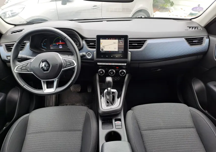 Vue intérieure frontale du tableau de bord et console centrale du Renault Arkana 2023 avec sellerie tissu noir et insert bleu Zanzibar.