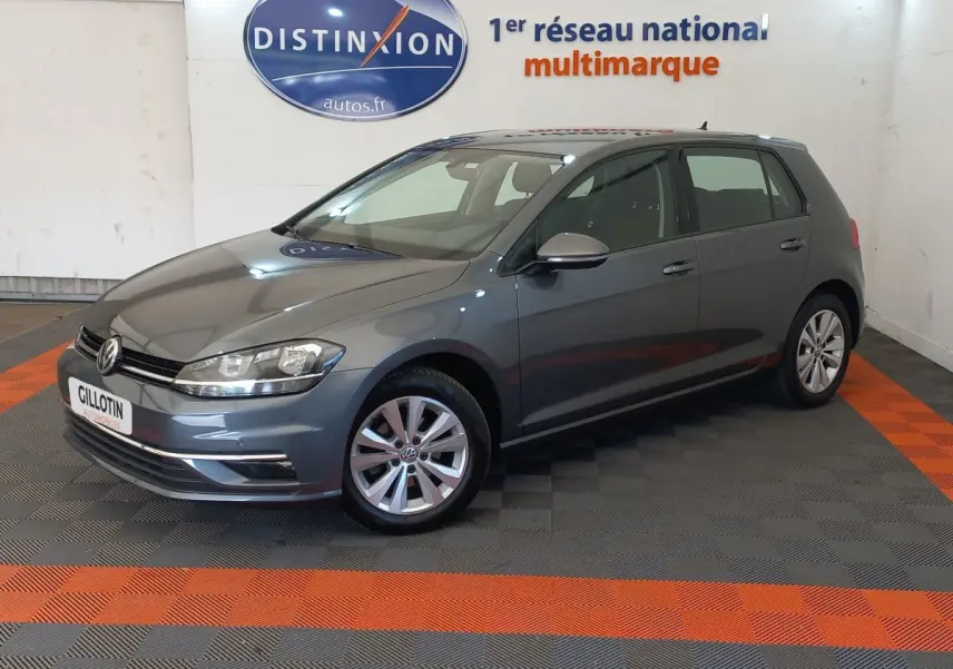 Volkswagen Golf gris foncé vue 3/4 avant droit en intérieur, avec jantes alliage et calandre chromée.