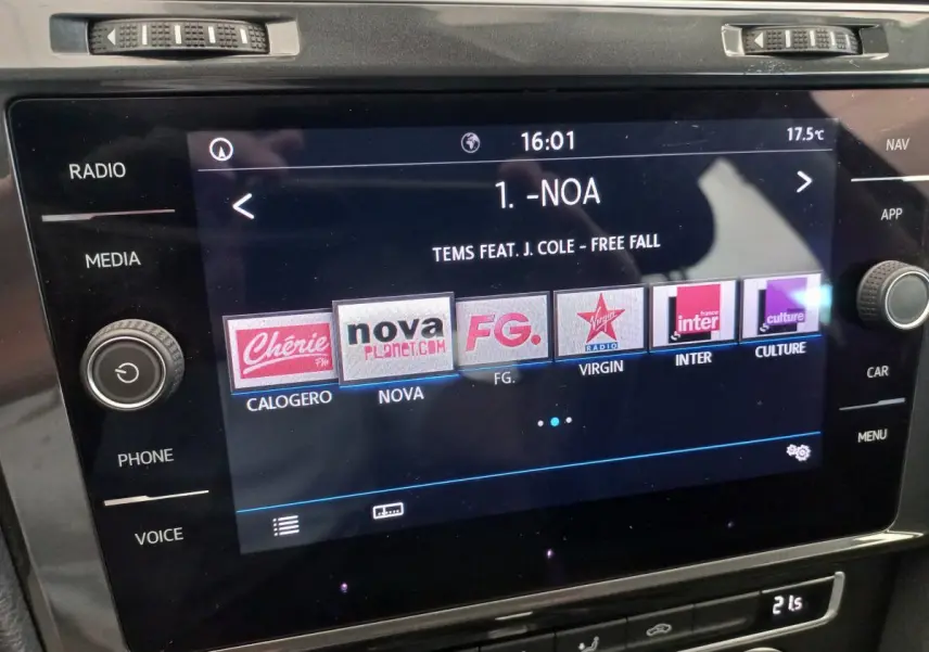 Écran tactile central de la Volkswagen Golf gris foncé 2019 affichant les stations radio et la chanson en cours.