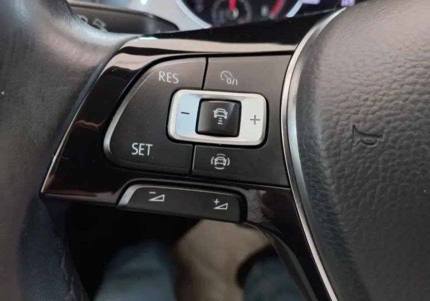 Gros plan sur les commandes du régulateur de vitesse au volant cuir noir de la Volkswagen Golf gris foncé 2019.