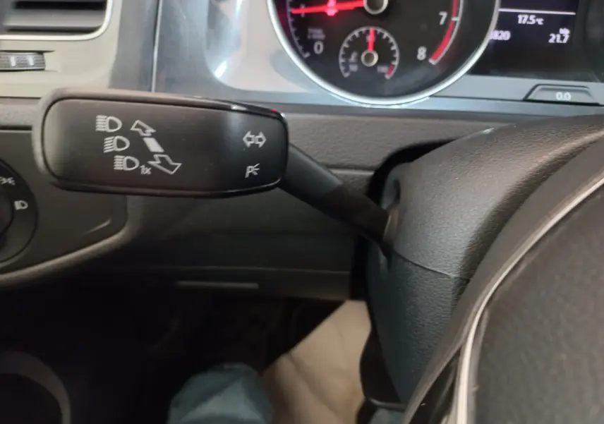 Gros plan sur la manette de clignotants à gauche du volant dans l'habitacle gris foncé d'une Volkswagen Golf 2019.